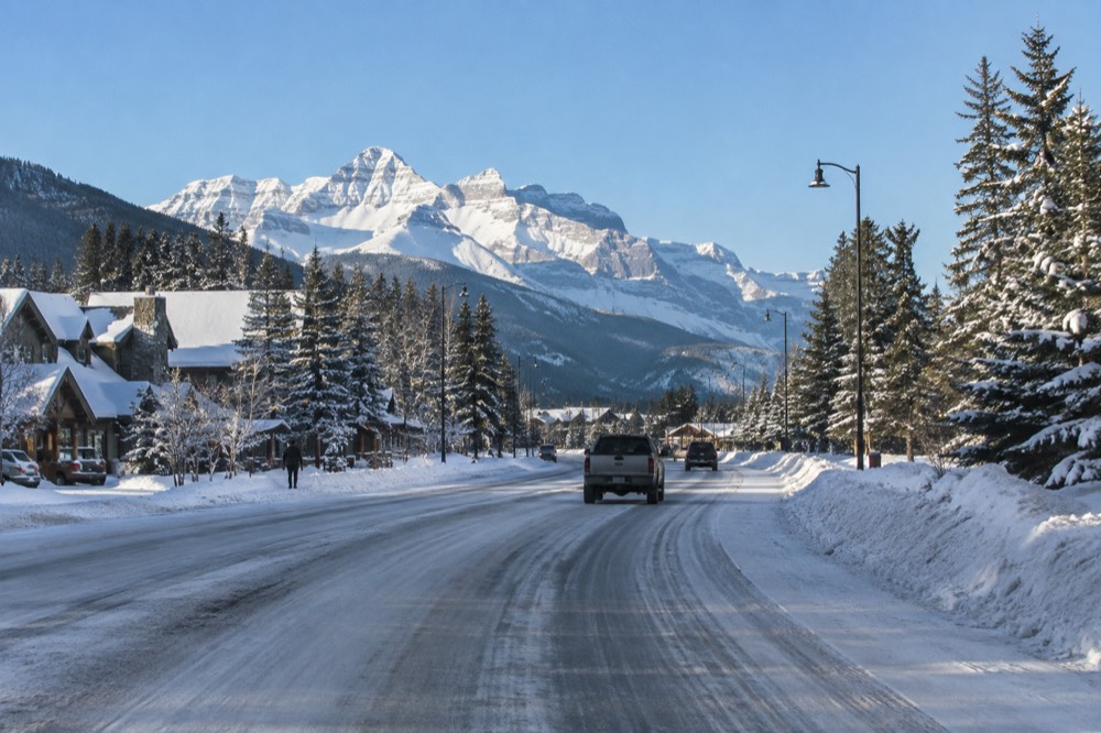 A snow-lined mountain highway winding toward a distant icefield under a cold clear sky
