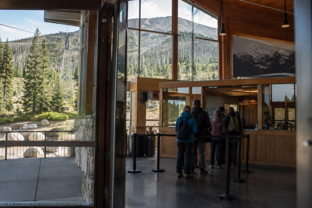 Ticket counter and boarding queue at a mountain gondola base station on a clear morning