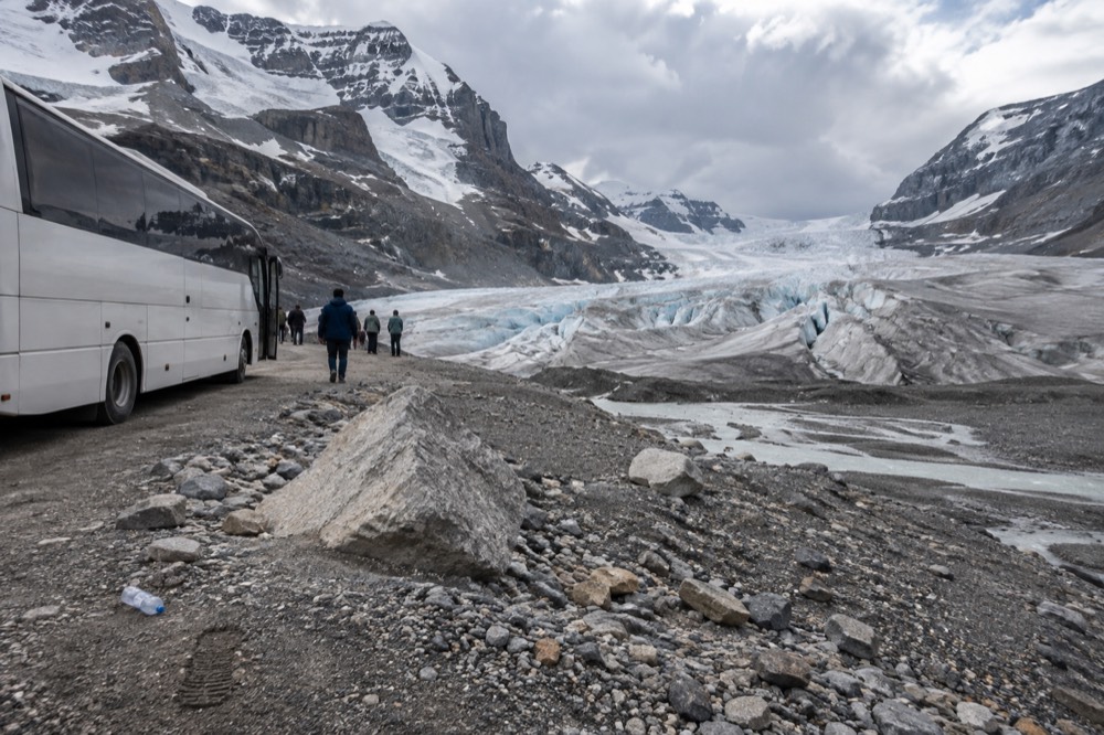 A tour bus parked at a glacier viewpoint with a wide icefield beyond