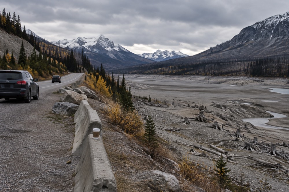 A roadside pullout above a wide glacial valley with a long empty highway stretching south