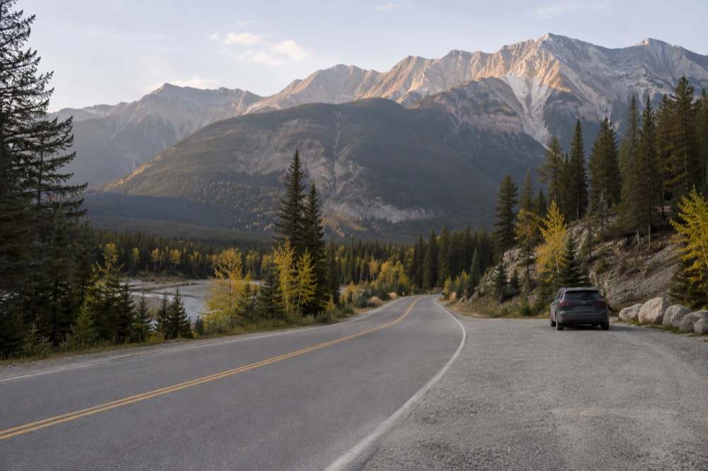 An empty winding road through a mountain valley in early morning light