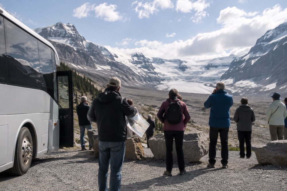 A tour vehicle parked at a viewpoint overlooking a glacier and a wide mountain valley