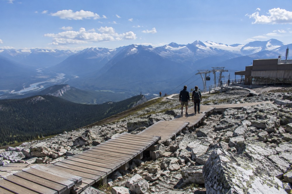 Boardwalk and rocky alpine slope near a mountain summit station under a wide sky