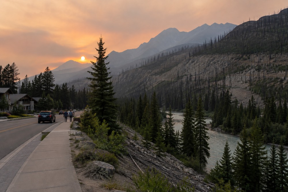 Steep forested mountain slopes rising above a river valley in the Rockies