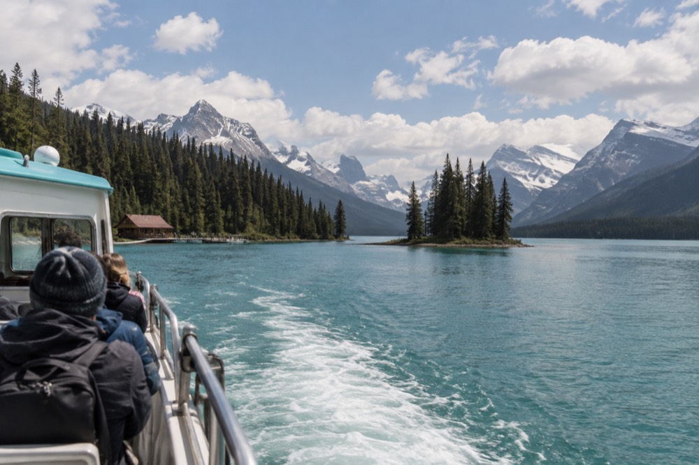 Tour boat crossing a long glacial lake toward a small forested island