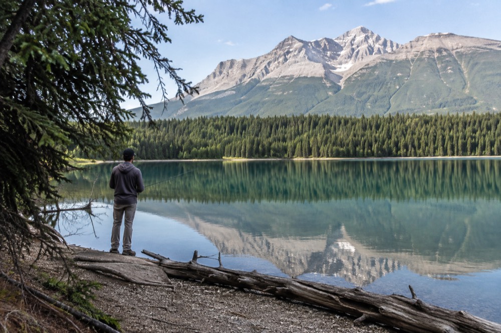 A turquoise mountain lake ringed by pine forest with peaks reflected on calm water