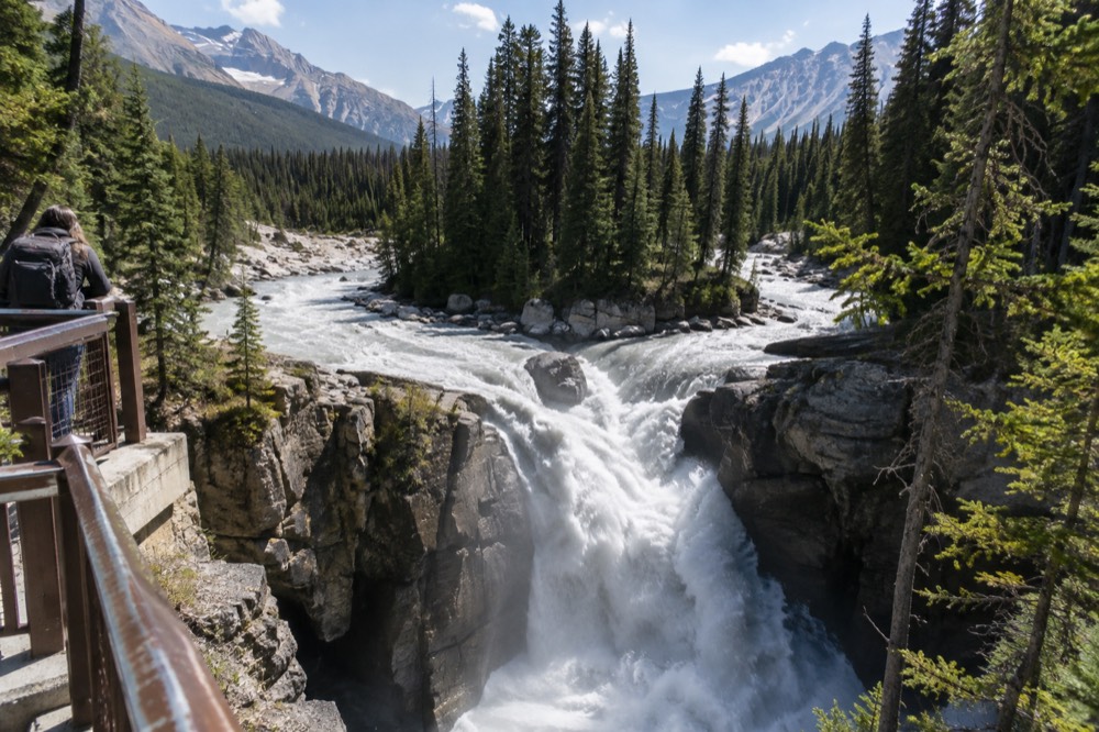 A powerful waterfall pouring through a narrow rock canyon with mist rising