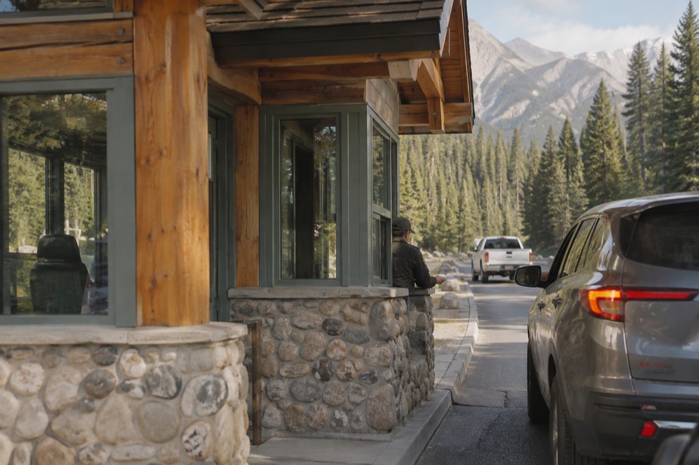 A park entry gate booth on a highway with forested mountains beyond