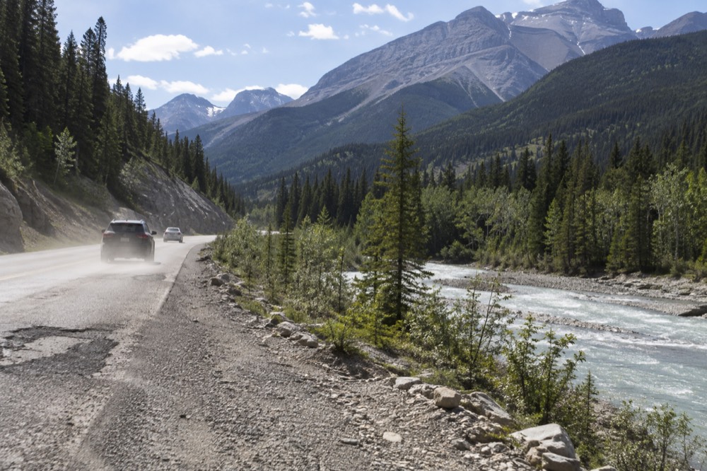 A winding mountain road following a river through a forested valley